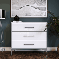 White dresser with three drawers in a room setting.