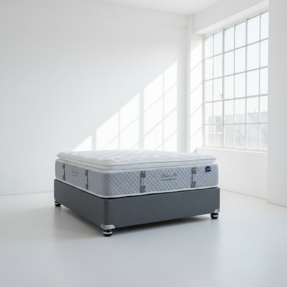 Two mattresses stacked on a gray floor with a neutral background