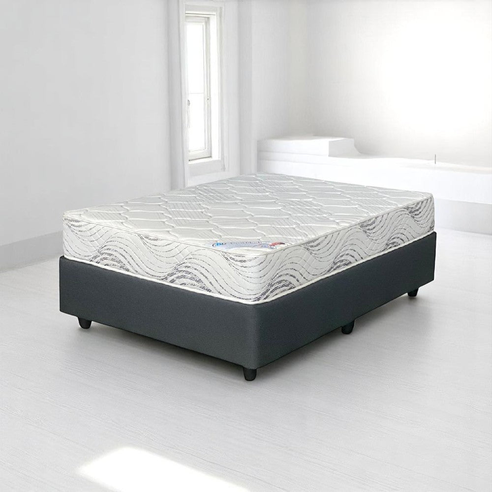 Mattress on a bed frame in a minimalistic room with white walls and floor.