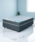 Gray mattress on a white marble floor with a light blue wall and plant in the background
