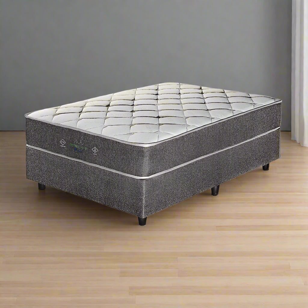 A gray plush pillow top queen mattress on a foundation, designed for comfortable sleep.