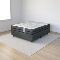 Mattress on a white rug in a room with wooden flooring and white walls