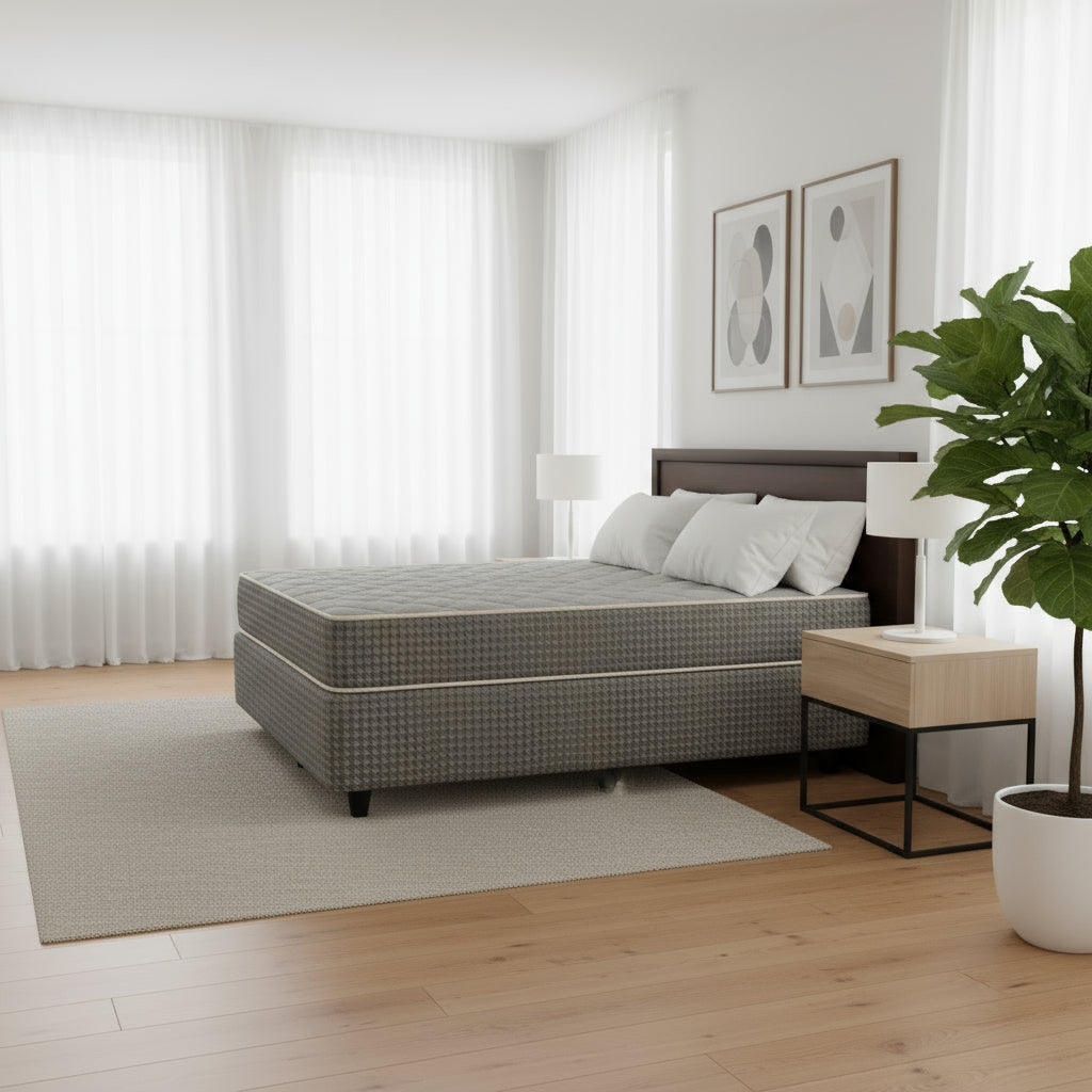 A beige, upholstered double bed set with a firm mattress, placed on a bed frame with visible wooden legs.