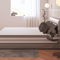 Bedroom with a neatly made bed featuring a mattress topper, pillows, and a side table.